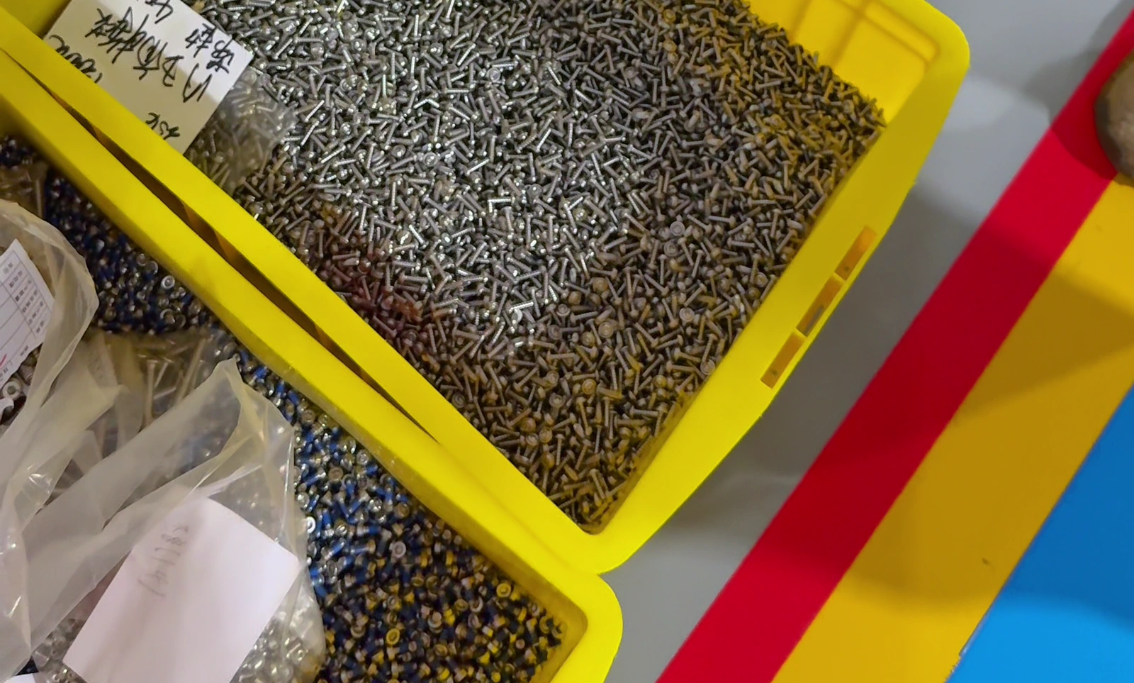 Fastener batches held in separate yellow bins in the rejected-parts area