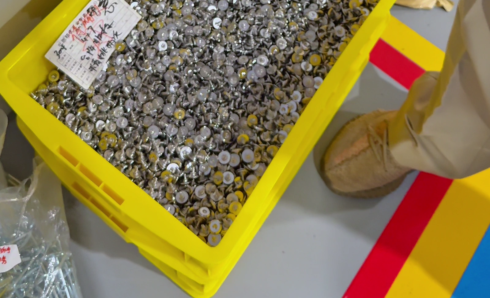 Rejected screw batch with its identification tag in a yellow bin